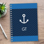 SparkGreetings® Nautical Anchor Writing Journal, navy blue notebook with white anchor graphic and initials GT, spiral-bound on wooden desk.
