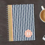 SparkGreetings® Triangles & Glitter Writing Journal, a navy blue and white triangle patterned journal with pink and gold glitter accents and a personalized initial B on the cover.