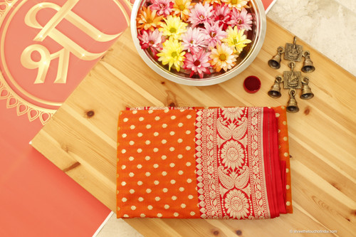An orange-red silk saree with golden zari for timeless traditions