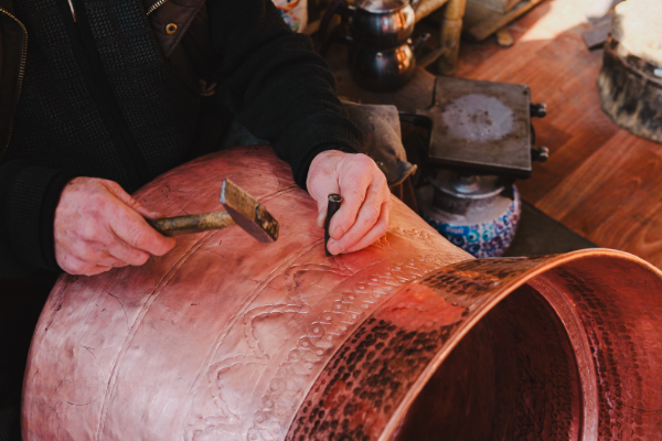Artisan hammering a copper planter