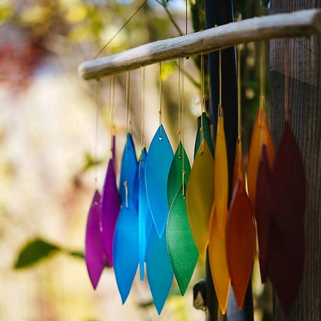 Multi-colored crystal wind chimes hanging from wooden fence post