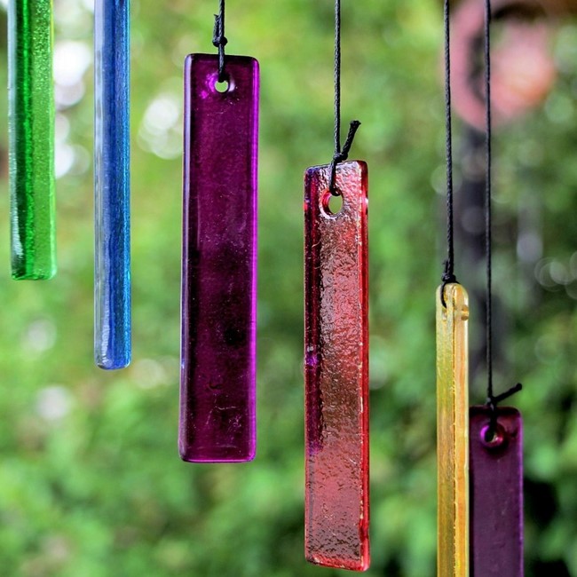 Multicolored glass charms hanging from black cords on outdoor wind chimes