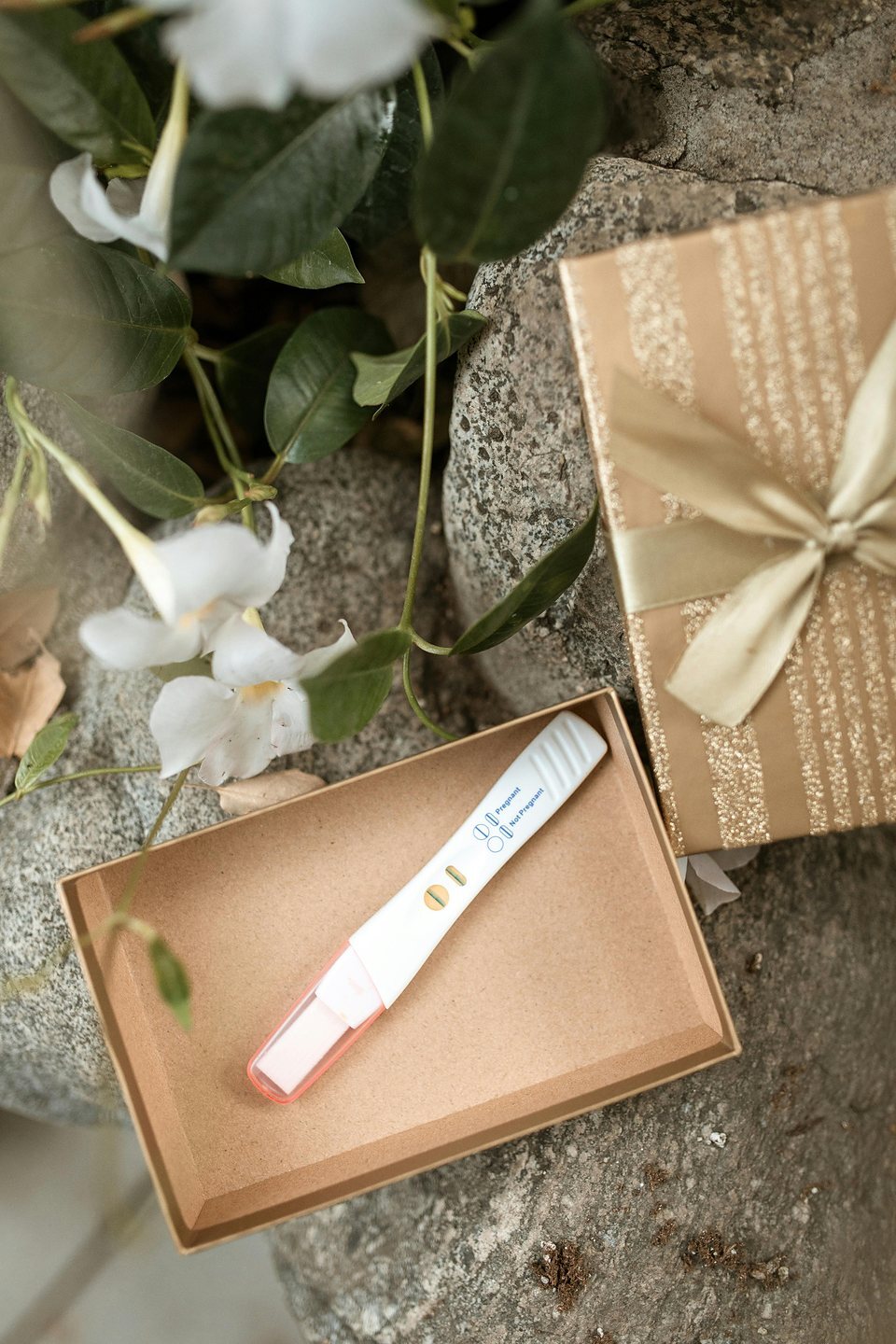 Pregnancy test in a gift box with flowers