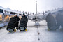 Two technicians roll loaded Smart Cart Automatic Tire Cart units across a snowy work area with stacks of tires secured upright on the frames. The photo shows how the cart moves multiple tires at once in a real shop setting.