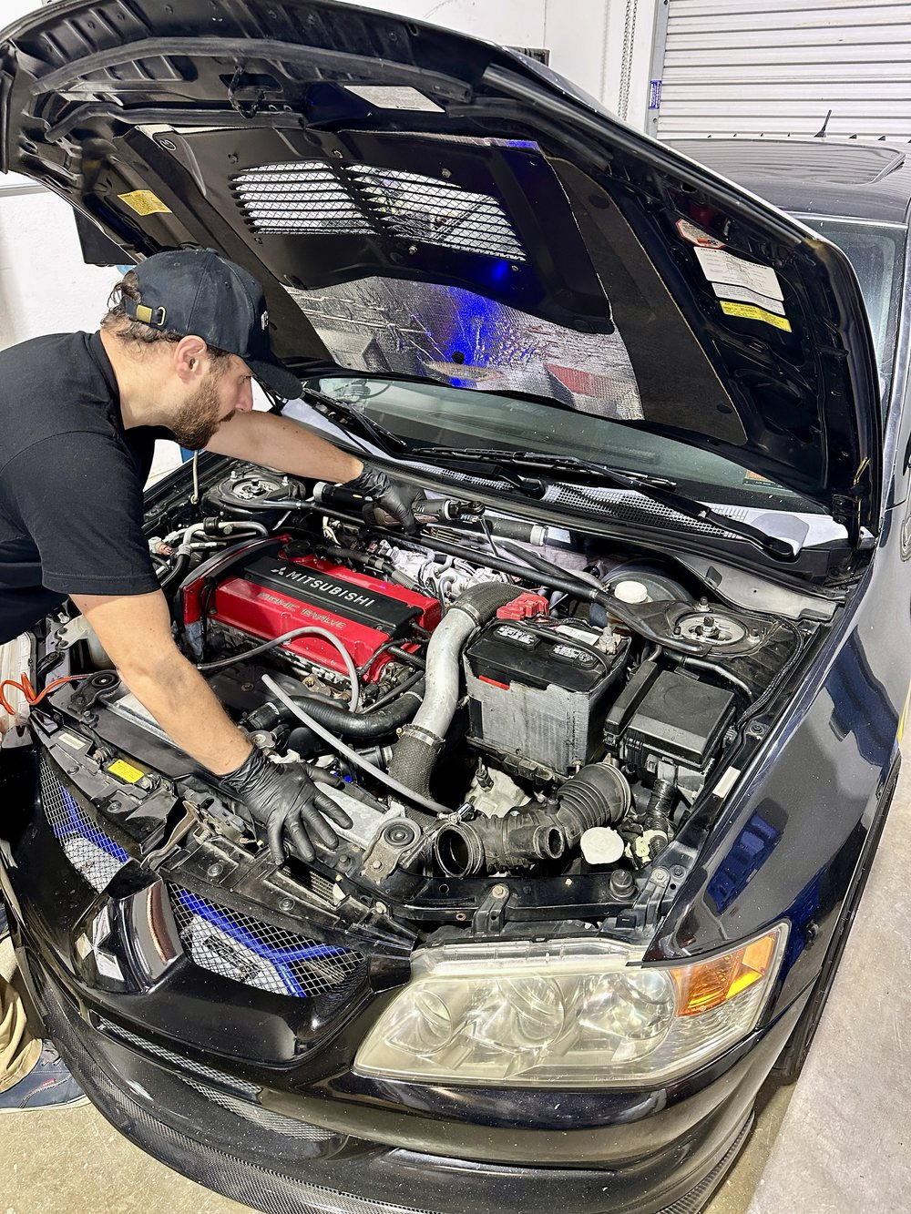 Technician working on a Mitsubishi Evo engine bay in the shop