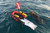 Red and yellow inflatable dive board with dive flag floating in ocean water, overhead view