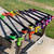 Multiple colorful spearguns displayed on rack including MAKO Primline Mean Green rubber speargun band tubing models in various colors with accessories
