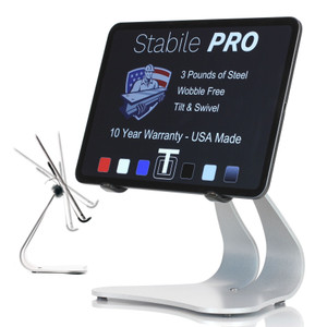 Stabile PRO silver steel iPad stand holding an iPad in landscape orientation, screen displaying features: 3 pounds of steel, wobble free, tilt and swivel, USA made 10 year warranty. Small inset shows tilt motion range on left.