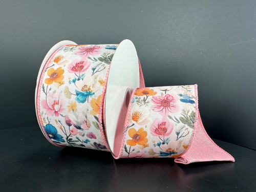 A 2.5 inch wide roll of light-colored poly linen wired ribbon featuring a dense pattern of vibrant pink, orange, and yellow wildflowers with a pink stitched edge.