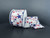 A 2.5 inch wide roll of white satin wired ribbon featuring a festive burst pattern of red and blue glittered stars and starburst accents.