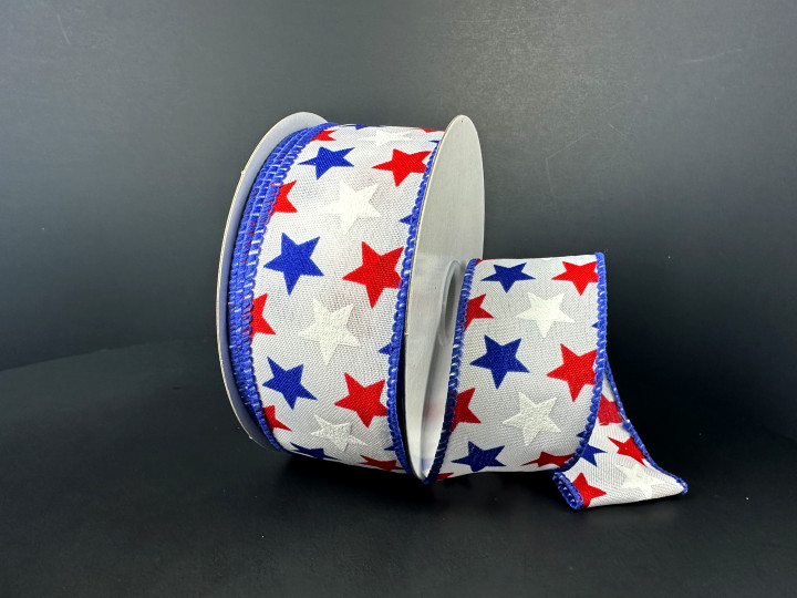 A 1.5 inch wide roll of white satin wired ribbon featuring a scattered pattern of solid red, blue, and white stars with a decorative blue stitched edge.