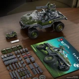 Hot Wheels UNSC M12 Warthog Hot Wheels Brick Shop Halo 935-Piece 1:22 Building Set (25th Anniversary), assembled olive-green brick-built Warthog with turret beside a mini vehicle, instruction booklet, and assorted building pieces on a wooden table.