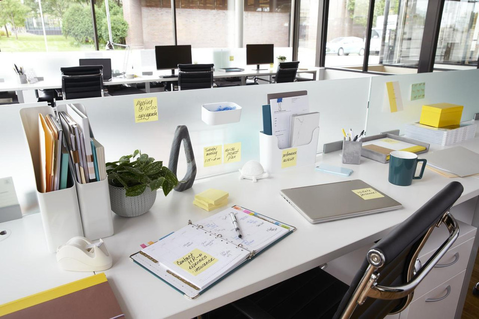 Post-it Z Notes 76x76mm 100 Sheets Canary Yellow Pack 12, office desk with yellow sticky notes on a partition, notebooks, laptop, mug, and office supplies in a modern workspace.