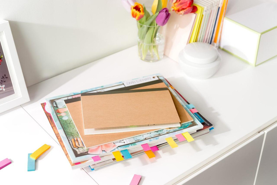 Post-it Note Paper Index Flags Repositionable, 15x50mm, assorted colors, pack of 500 tabs, on a white desk with notebooks and flowers.