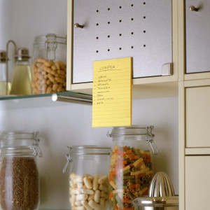 Post-it Super Sticky Notes 102x152mm Ruled 75 Sheets Ultra Yellow, yellow ruled sticky notes attached to a metal cabinet in a kitchen setting.