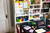 Post-it Super Sticky Notes Playful Colours 76x127mm 90 Sheets Pack 6, colorful sticky notes in yellow, pink, purple, blue, and green on a cluttered desk with books, stationery, and a tablet, in a home office or study room.