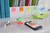 Post-it Super Sticky Notes 47.6x47.6mm 90 Sheets Cosmic Colours pack of 12, colorful sticky notes on a white desk with office supplies.