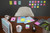 Post-it Post-It Super Sticky Notes 76x127mm 90 Sheets Cosmic Colours Pack 6, colorful sticky notes in pink, yellow, blue, green, and purple on a desk with office supplies and a black wall with colorful sticky notes in the background.