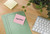 Post-it Post it Recycled Notes Assorted Colours 38x51mm 100 Sheets Pack 6, image showing colorful sticky notes, a planner with Notes written on pink paper, and a computer keyboard on a wooden desk.