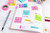 Post-it Note Cube 76x76mm 450 Sheets Pastel Blue 2028B - 7100172385, image of a cube of pastel blue sticky notes on a desk with various office supplies and handwritten notes on a planner.