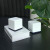 Various Mercusys Halo H50G (3-pack) AC1900 Whole Home Mesh Wi-Fi System, 600 Mbps at 2.4 GHz + 1300 Mbps at 5 GHz, 3x Internal Antennas, includes three white rectangular nodes with black bases placed on a white box on a black desk with a plant in the background.