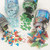 CW Office Christmas Sequins Shaker AST 50G PK4, colorful holiday themed confetti including snowflakes, Christmas trees, Santa, reindeer, and holiday words in various colors poured out of jars.