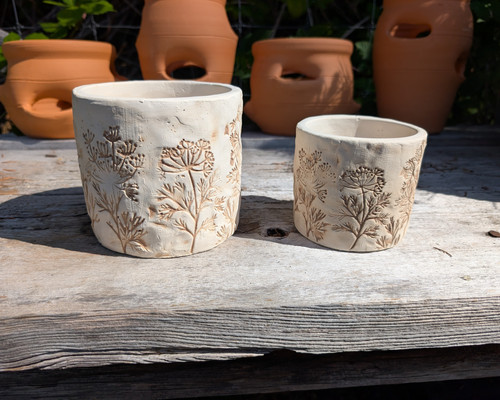 Natural cement planter with embossed wildflower design.