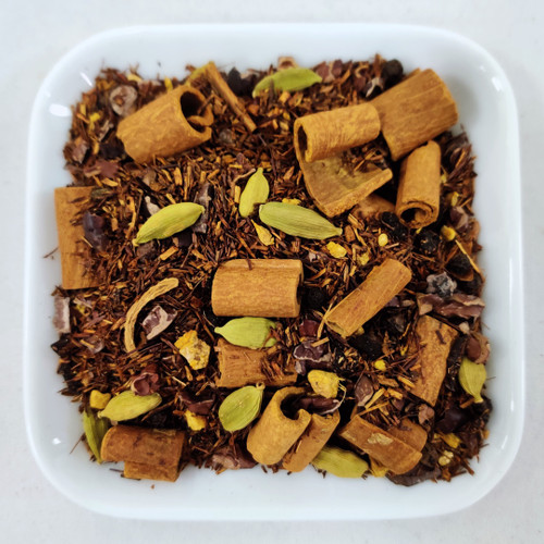 En bild på teet Nelson Mandela som innehåller röd rooibos, kanel, kakao, kardemumma, ingefära, peppar, och cikoriarot. De bryggda teet har en röd-brun färg.  Bladen är röda, bruna och gröna, med stora bitar av kanel och kardemumma. 