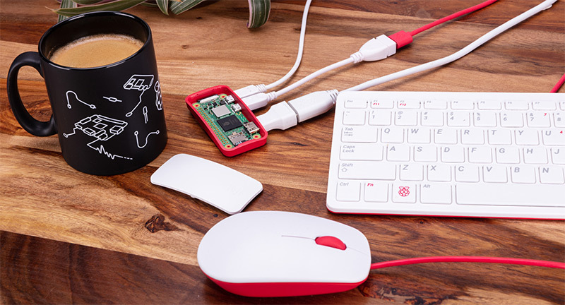 Raspberry Pi Zero 2 W connected to keyboard, mouse, and accessories on a wooden desk