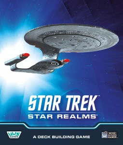A board game titled “Star Trek: Star Realms” in white font at the bottom of the cover. The art above is a scene in space bathed in blue light. In the centre is a silver spaceship with a large disk that makes up the majority of its mass. It has a neck that comes down to connect to a rounded body. From either side of that body are arms that connect to elongated engines that glow red on their fronts. This is an iteration of the Starship USS Enterprise. A board game titled “Star Trek: Star Realms” in white font at the bottom of the cover. The art above is a scene in space bathed in blue light. In the centre is a silver spaceship with a large disk that makes up the majority of its mass. It has a neck that comes down to connect to a rounded body. From either side of that body are arms that connect to elongated engines that glow red on their fronts. This is an iteration of the Starship USS Enterprise.