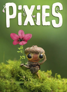 A board game titled "Pixies" in large, white font at the top of the small cover.  The art below features a photograph taken in a vibrantly green forest.  Moss in the foreground carpets where a little pixie made of acorns, sticks, and with large, black eyes smiles while holding a pink flower's stem that is large enough to serve as a walking stick for a creature of its size.
