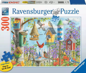 A puzzle with the words “Ravensburger Puzzle” at the top and the number ‘300’ along the left side of the white bordered cover. Below is an image of the finished puzzle, which features a cluster of birdhouses of different shapes, colors, and sizes that are nailed to trees. Perched on, flying around, or peeking out of them are similarly diverse birds. Flower bushed bloom behind them. A puzzle with the words “Ravensburger Puzzle” at the top and the number ‘300’ along the left side of the white bordered cover. Below is an image of the finished puzzle, which features a cluster of birdhouses of different shapes, colors, and sizes that are nailed to trees. Perched on, flying around, or peeking out of them are similarly diverse birds. Flower bushed bloom behind them.