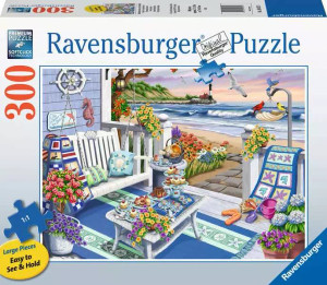 A puzzle with the words “Ravensburger Puzzle” at the top and the number ‘300’ along the left side of the white bordered cover. Below is an image of the finished puzzle, which features a beach-side scene from a white porch with flowers, chairs, and a squat table laden with tea and tea-related snacks. Seagulls circle hungrily overhead, awaiting the chance to snatch your goodies away. A puzzle with the words “Ravensburger Puzzle” at the top and the number ‘300’ along the left side of the white bordered cover. Below is an image of the finished puzzle, which features a beach-side scene from a white porch with flowers, chairs, and a squat table laden with tea and tea-related snacks. Seagulls circle hungrily overhead, awaiting the chance to snatch your goodies away.