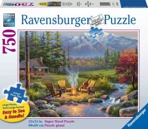 A puzzle with the words “Ravensburger Puzzle” at the top and the number ‘750’ along the left side of the white bordered cover.  Below is an image of the finished puzzle, which features an outdoor scene with a cluster of wooden lawn chairs circled around a fire pit in the foreground.  A meandering creek runs next to it, and behind is a log cabin with a golden light glowing in the window.  Behind all this is a picturesque mountain range.