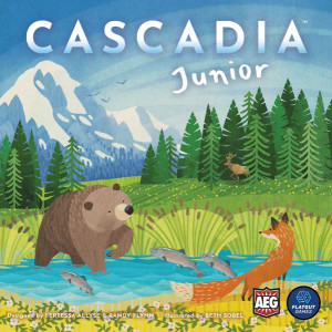 A board game titled "Cascadia Junior" in white font across the top of the square cover.  The art below is a collage and colored pencil-stylized piece depicting a scene in nature.  A bear and a fox stand on either side of a river filled with leaping fish and bordered by cattail plants.  A moos stands in the distance at the edge of a treeline, and snow capped mountains tower beyond the trees under a bright blue sky.