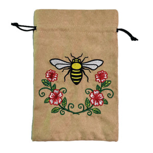 A tan dice back with draw strings and an embroidered image of a honeybee with flowers beneath it.