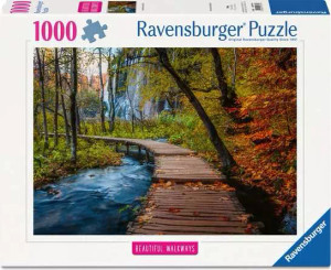 A puzzle with the words “Ravensburger Puzzle” at the top and the number ‘1000’ along the left side of the white bordered cover.  Below is an image of the finished puzzle, which features a photograph of a wooden plank trail curving along a forest floor.  The foliage around it is spotted with red, and leaves fall from above.  The trail crosses a blue creek in the foreground.