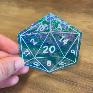 A holographic 20-sided die with white numerals being held by a hand above a wooden table.