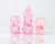 A full sparkling pink dice set by Sirius Dice mixed with iridescent green flakes