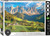 The image is a puzzle box that features a scenic landscape of the Italian Alps in the Dolomites. The foreground features a lush, green valley with scattered small buildings, including a church with a tall steeple surrounded by green fields and dense coniferous forests. In the background, a dramatic range of rocky, jagged peaks rises under a partly cloudy sky, illuminated by warm sunlight. The title, "Dolomites - Italian Alps" is printed along the bottom edge. On the right hand edge, the company logo reads "EUROGRAPHICS PUZZLES" in white text on black background and the number ‘1000’ after it indicates the puzzle piece count. In the bottom left, there is a picture of a camera lens with the words "HDR Photography - Scenic Landscape" printed on the inside rim of the lens.