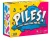 A board game titled “Piles!” in large, white font across the center of the cover.  Behind the title is a drawing of a pile of laundry colored entirely in shades of blue, and behind that is a half yellow, half hot pink background.