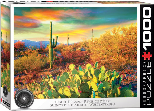 A Eurographics puzzle titled "Desert Dreams" that is a sunset scene from a desert.  The sky is streaked in rainbow colors across the clouds.  Yellow and red bushes with the occasional green cactus colors the landscape, some of the last sporting little pink fruits.  A mountain range cuts across the skyline in the distance.