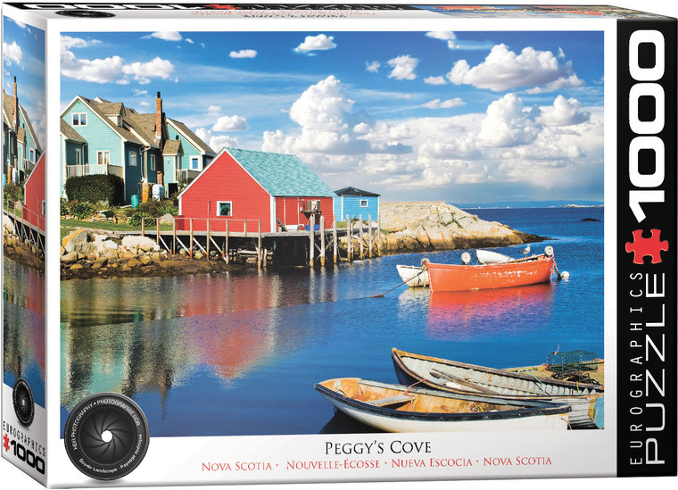 The image features Peggy’s Cove, a scenic coastal village in Canada. In the foreground, calm blue water reflects the vibrant colors of buildings and boats. A weathered red fishing boat with white trim is moored in the water alongside smaller boats. Along the shoreline, colorful houses sit atop a rocky landscape. The most prominent house is red with a pale blue roof, sitting on wooden stilts over the water. Adjacent to it are teal and blue buildings. The sky overhead is bright with scattered, fluffy white clouds. The title, "Peggy's Cove, Nova Scotia" is printed along the bottom edge. On the right hand edge, the company logo reads "EUROGRAPHICS PUZZLES" in white text on black background and the number ‘1000’ after it indicates the puzzle piece count. In the bottom left, there is a picture of a camera lens with the words "HDR Photography - Scenic Landscape" printed on the inside rim of the lens.