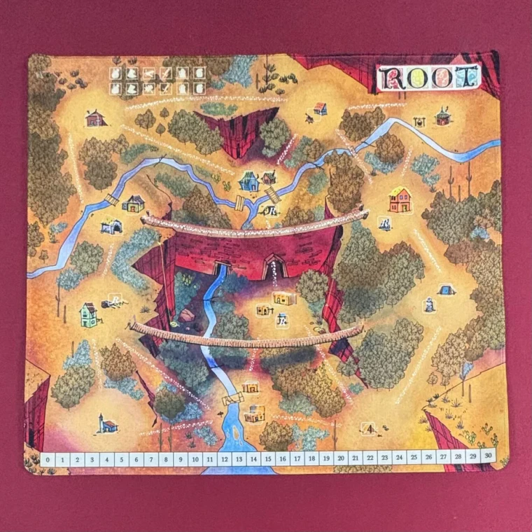 A board game playmat featuring an illustration of a forest with roads, wooden bridges, streams, and settlements dotting the board.  The word "ROOT" is written in gothic font backed by colorful filigree atop a piece of parchment in the upper right hand corner.