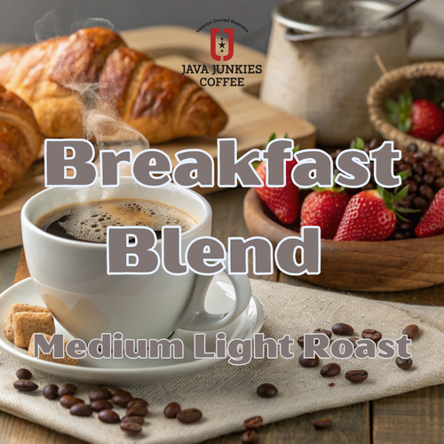 Java Junkies Breakfast Blend Coffee. Coffee cup full of coffee on a saucer next to some fresh strawberries and pastries sitting on a table with cream.
