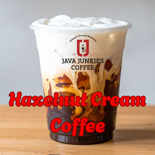 Java Junkies Hazelnut Cream Coffee. 24oz cup of Iced coffee floating heavy cream on top sitting on a wood counter.