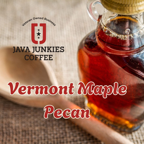 Java Junkies Vermont Maple Pecan Coffee.  Clear bottle of maple syrup sitting next to a wooded spoon sitting on a burlap bag.