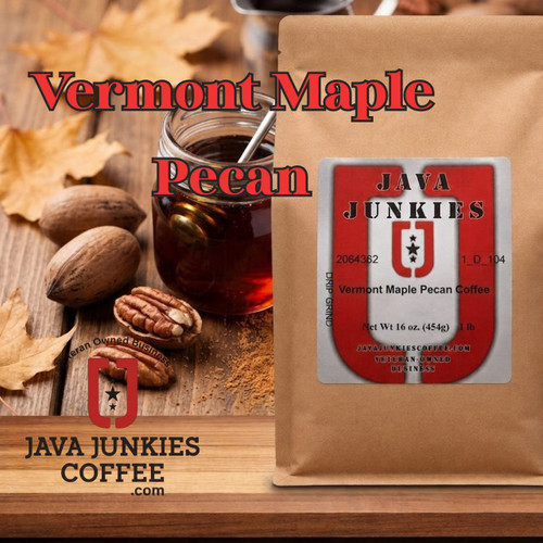 Java Junkies Vermont Maple Pecan Coffee.  Clear bottle of maple syrup sitting next to some pecans with leaves sitting on some dark wood.