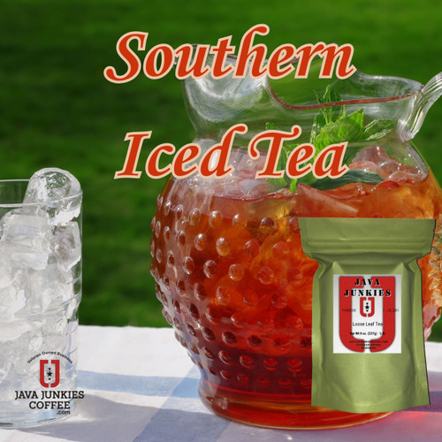 A large hobnail glass pitcher filled with iced tea, ice cubes, and fresh mint leaves sits on a table next to a tall glass filled with ice.