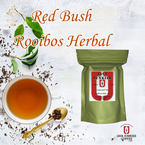 Red Bush Rooibos herbal loose leaf tea pouch, cup of tea, spoon, and fresh green leaves displayed on a textured white wooden background.